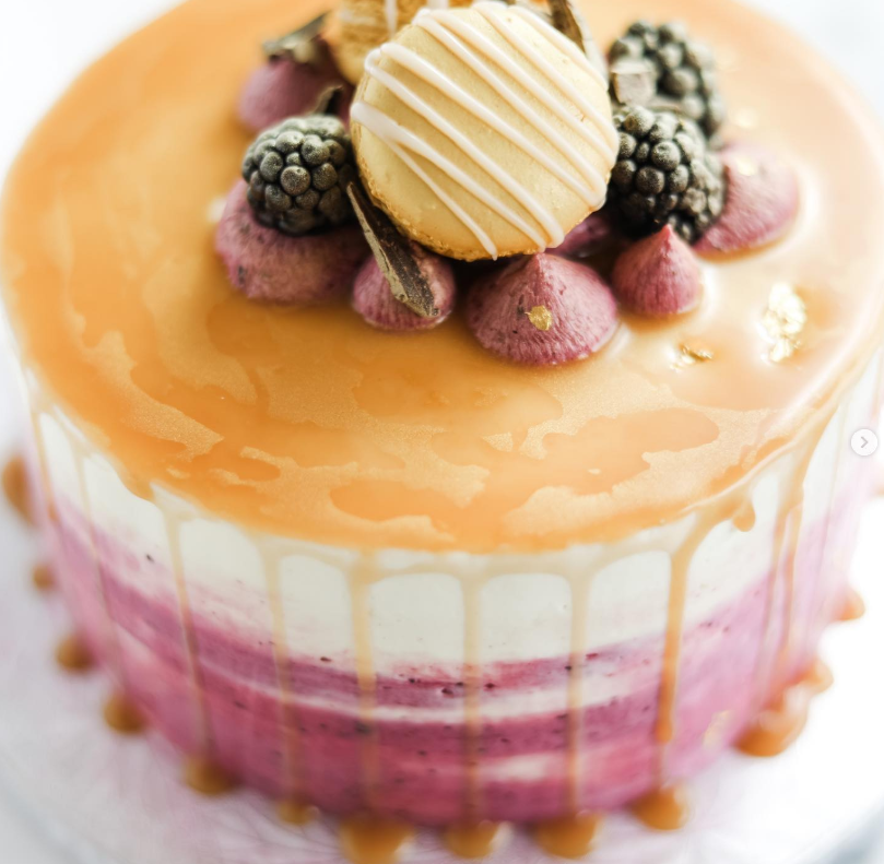 Caramel-glazed cake topped with blackberries, macarons and berry buttercream kisses