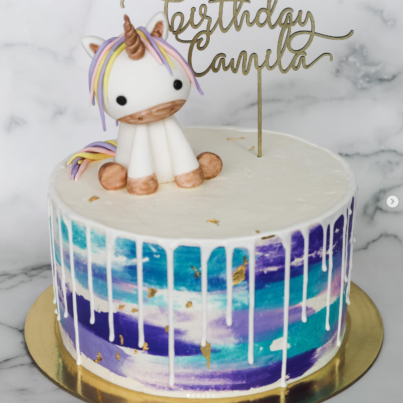 Watercolor birthday cake with a sculpted unicorn topper